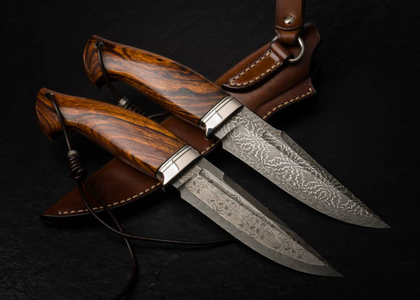 Close-up of a finely crafted chef's knife resting on a textured box. The blade showcases intricate Damascus patterns, highlighting the artistry and skill in its creation. Placed on a rustic wooden surface, exuding a blend of tradition and modern culinary craftsmanship
