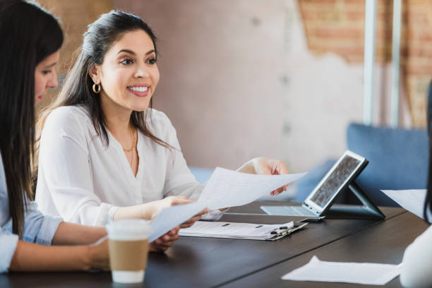istock Two Women in Business Casual Discussing Documents 2196229509