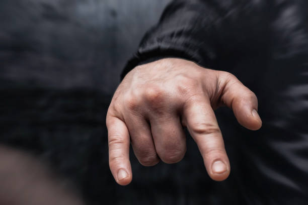 istock Close-up of a man in a shirt shows hand gesture Rock'n'roll against a concrete wall. 2196229708