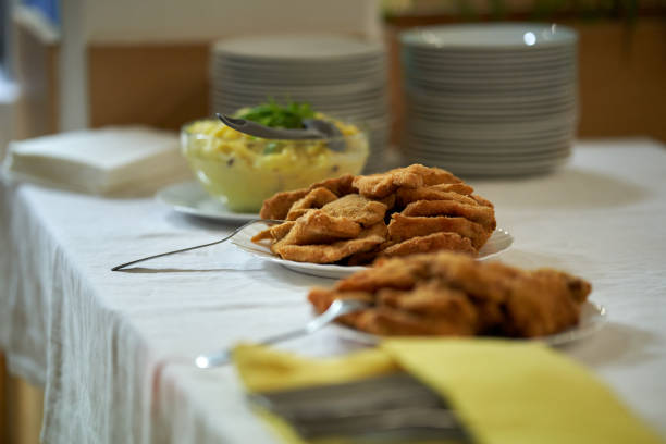 A bright and inviting scene showcasing delicious breaded fried food on a linen-covered table. A fresh salad bowl and neatly stacked plates complement the culinary display.