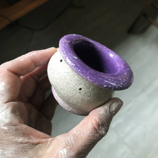 Close up shot of a hand holding a newly made small clay cup with nice shape and color. Taken in Quebec, Canada, during the day.