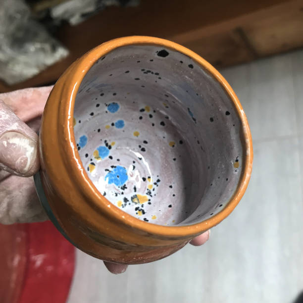Close up shot of a hand holding a newly made small clay cup with nice shape and color. Taken in Quebec, Canada, during the day.