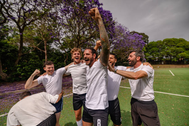 A joyful group of young men celebrates a successful soccer match on a vibrant field in Sydney, Australia. Their laughter and enthusiasm highlight the spirit of teamwork.