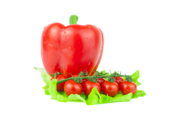 Two bright red tomatoes and a red capsicum with green stalk in a group
