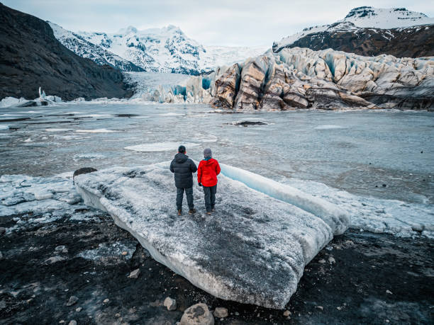 high angle rear view Asian chinese mature couple looking at camera smiling in front of Iceland Svínafellsjökull glacier
