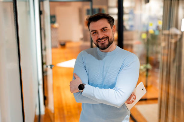 istock Confident businessman holding tablet and smiling in modern office 2196235558