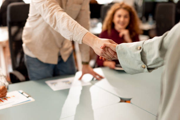 istock Professional Handshake in Office Setting with Colleagues Observing In Background 2196235694