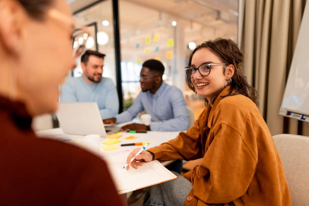 Young businesswoman taking notes and smiling during a meeting with colleagues