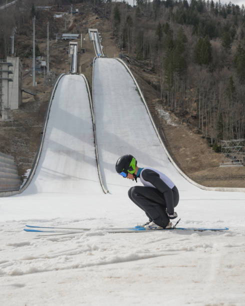 Young male ski jumper in the outrun at a training on snow.
