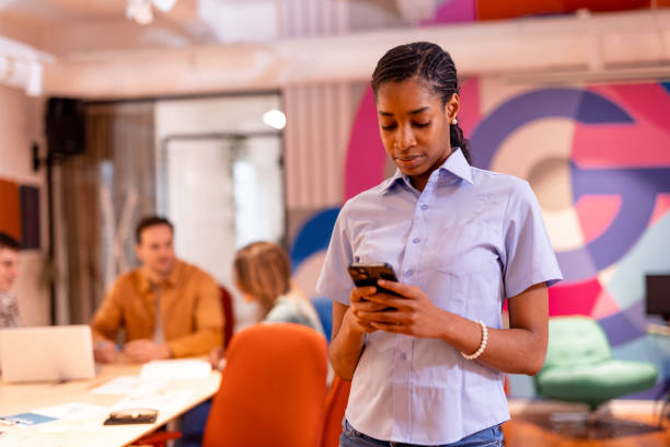 istock Young businesswoman using smartphone in modern office with colleagues working in background 2196237785