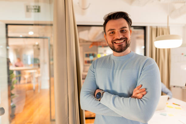 istock Confident businessman smiling with arms crossed in modern office 2196237972