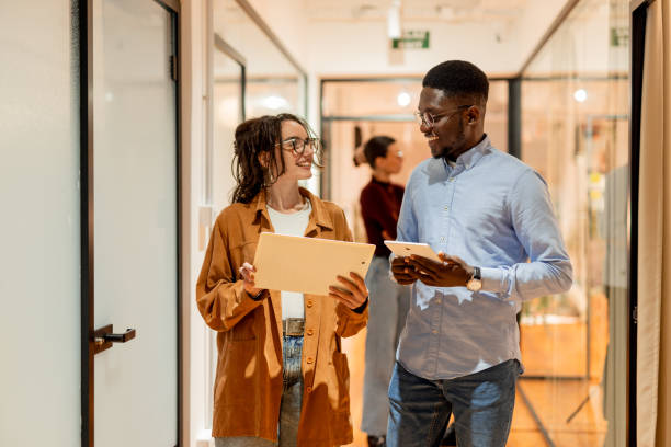 Young colleagues walking and talking in the office corridor