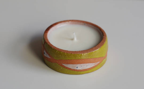 Shot of a candle in a handmade clay cup with unique shape and nice colors. Taken in Quebec, Canada, during the day.