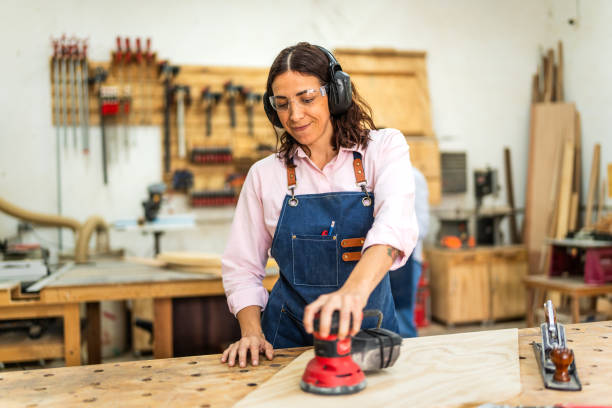 Mid adult woman using sander at carpentry