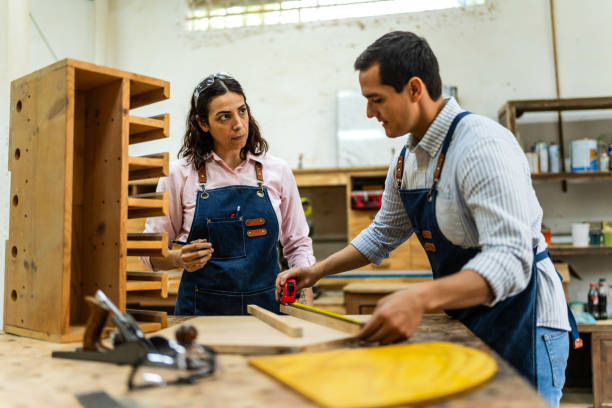 istock Mid adult carpenters talking and working at carpentry 2196240392