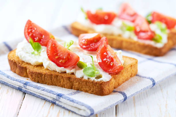 istock Healthy breakfast, bruschetta with ricotta cheese, and cherry tomatoes on a kitchen table. 2196240545