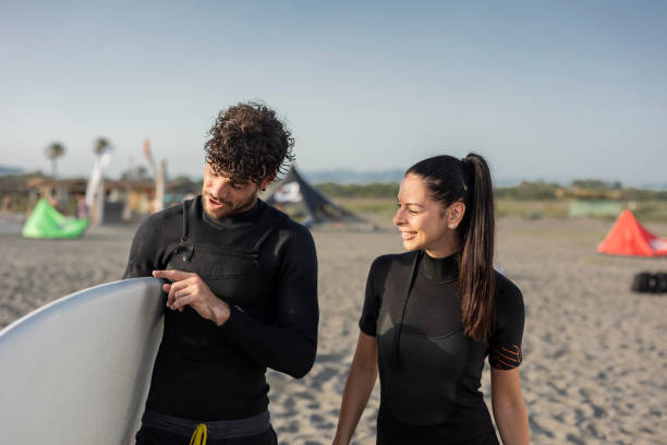 istock Kitesurfing instructor showing surfboard to smiling student on beach 2196241204