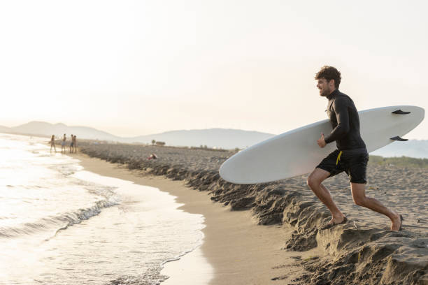 istock Surfer running towards ocean waves at sunset 2196241285