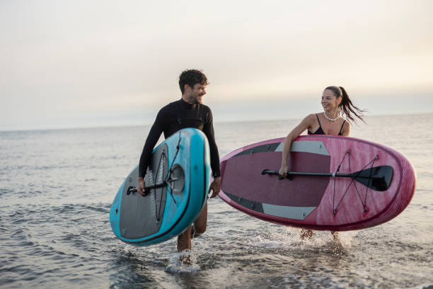 istock Couple exiting water after stand up paddling session at sunset 2196241454