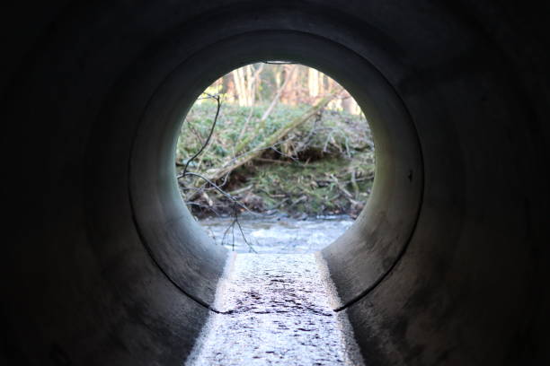 istock View through a round concrete tunnel carrying a stream beneath a road 2196242625