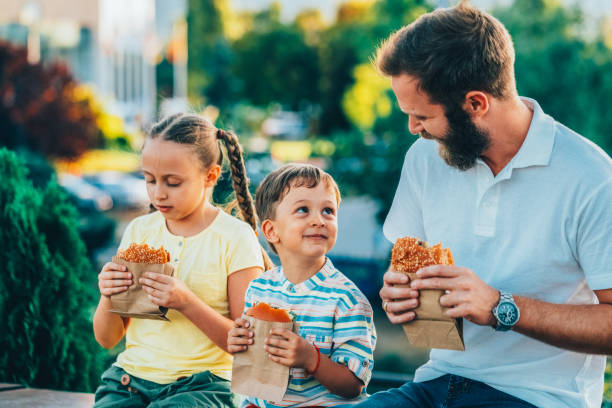 Single father with kids eating fast food outside