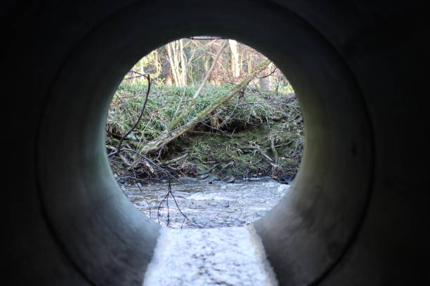 istock View through a round concrete tunnel carrying a stream beneath a road 2196242744