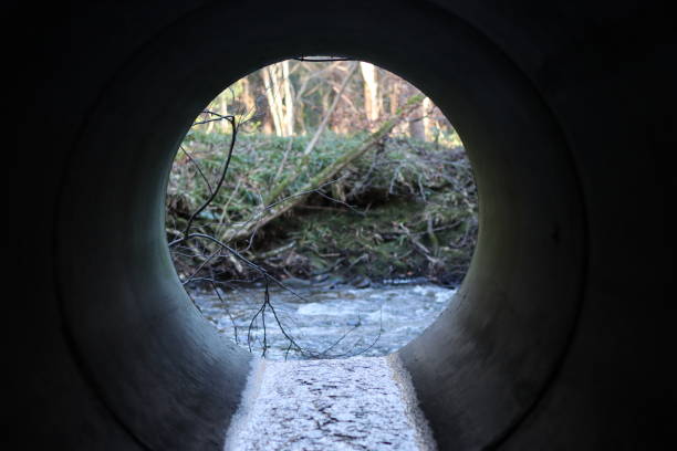 istock View through a round concrete tunnel carrying a stream beneath a road 2196242809