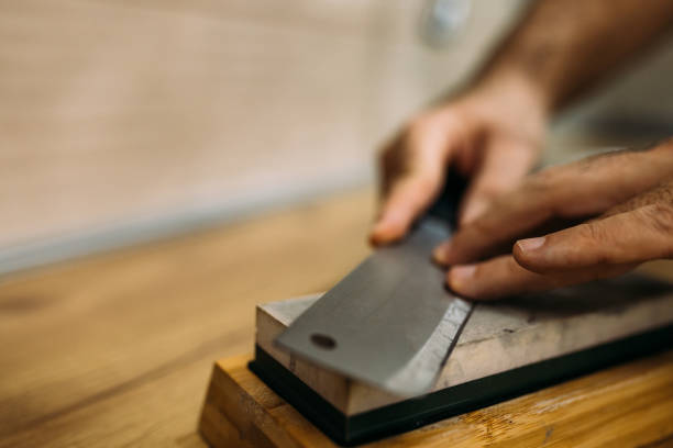 Senior craftsman knife maker making unique handmade stainless steel knives in his modern workshop.