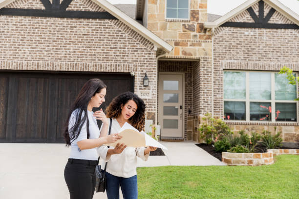 istock Two Women Reviewing Documents in Front of New Home 2196248011