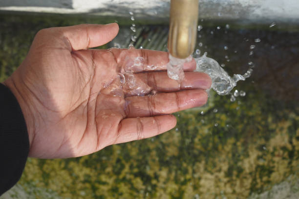 istock A Person Actively Catching Fresh Water Flowing from a Faucet, Emphasizing Cleanliness and Freshness 2196253019