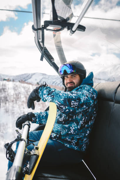 istock Man with Snowboard sitting on a Ski lift 2196257498