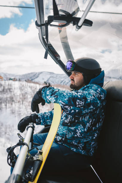 istock Man with Snowboard sitting on a Ski lift 2196257501