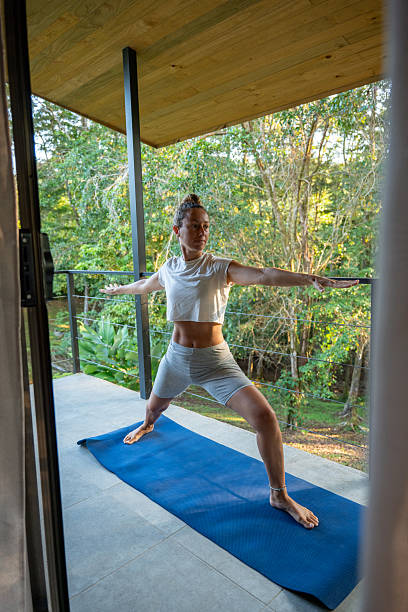 istock Woman Practicing Yoga on Porch with Forest View 2196258700