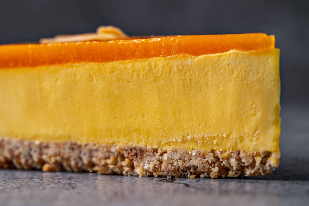 istock Slice of mango cheesecake with almond topping on a textured gray background 2196258729