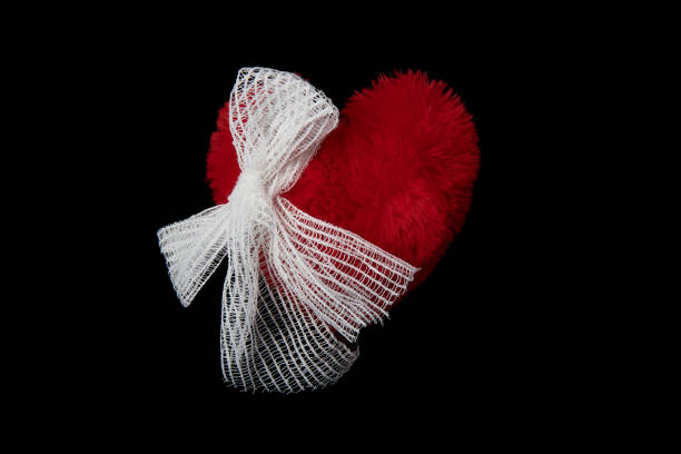 istock Fluffy red heart tied with white gauze on a black background 2196260792
