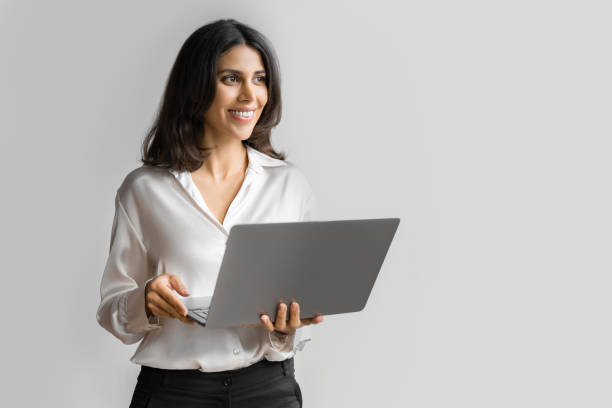 istock Young middle eastern businesswoman using laptop pc ai application for work isolated on white wall. Indian or arabic woman it specialist in business clothes holding computer, doing data base research 2196262821
