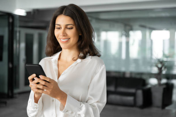 istock Portrait it specialist business woman manager ceo using cell phone mobile ai application for online work. Focused Latin Hispanic female businesswoman holding smartphone standing in office. Copy space 2196262830