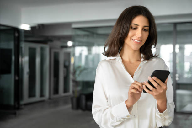 istock Young it specialist business woman manager ceo using cell phone mobile ai application for online work. Focused Latin Hispanic female businesswoman holding smartphone standing in office. Copy space 2196262831