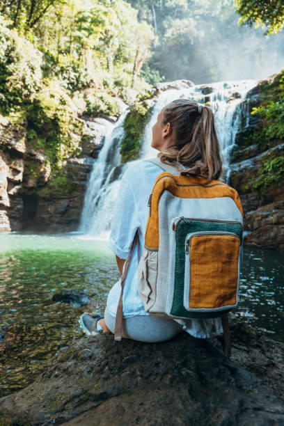 istock Young woman with backpack enjoying waterfall view in nature 2196264277