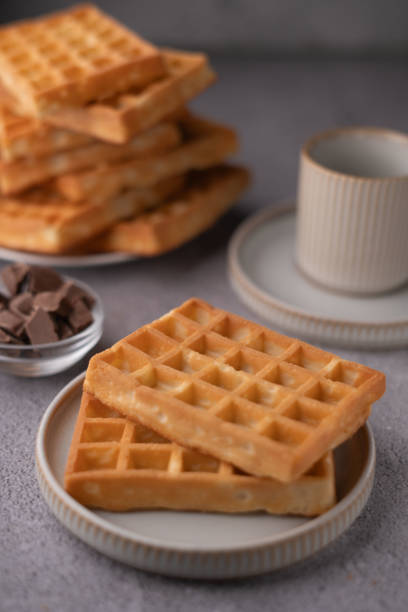 istock Delicious golden brown waffles stacked with chocolate pieces, artfully displayed on ceramic plates, ideal for breakfast or brunch food photography inspiration 2196268140