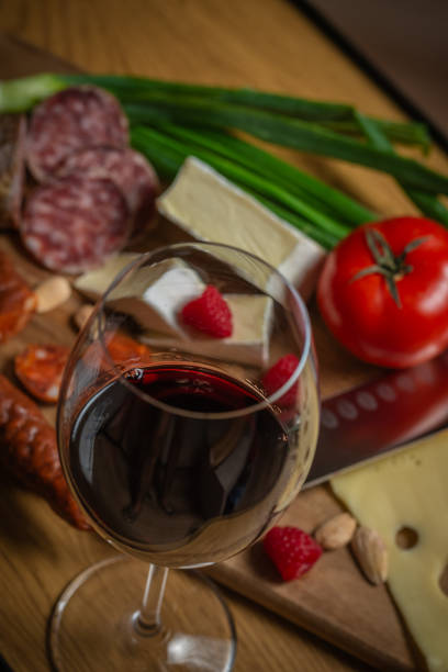 Bright sliced sausages and cheeses with vegetables and herbs lie on a board