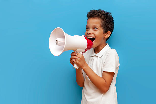istock Boy in white polo announces information into megaphone on blue isolated background 2196270501