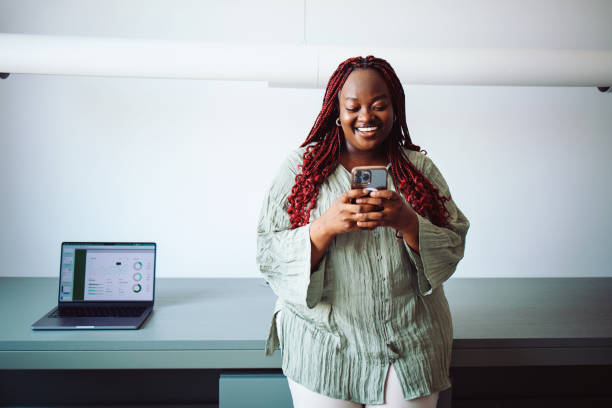 istock Smiling Woman Using Smartphone with Business Analysis Displayed on Laptop Nearby 2196271030
