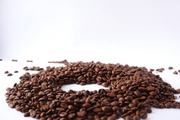 A carefully arranged pile of roasted coffee beans forming a circular shape on a clean white background, showcasing their rich brown color, texture, and association with creativity and coffee culture.