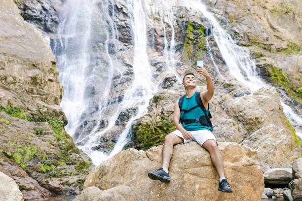 Young backpacker taking a selfie in front of scenic waterfall in colombia