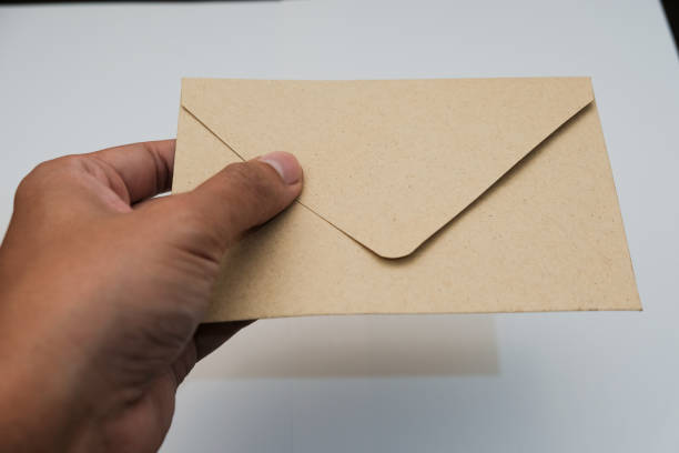 istock Closeup Male hands holding brown envelope isolated over white background 2196273838