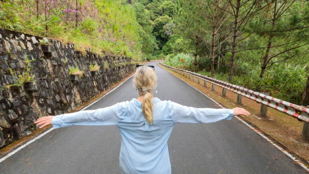 istock Mature woman hikes down road in pine forest 2196274382