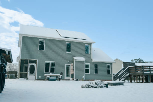 White two-story house with a triangular roof with a wooden fence on a snowy hill. High quality photo