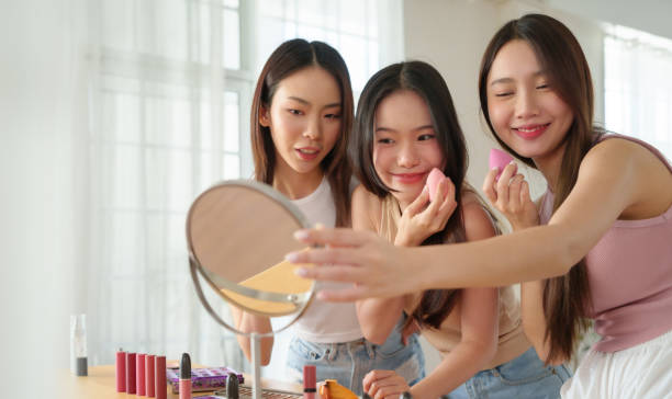 istock Three young Asian women enjoying a skincare session at home, smiling while using beauty sponges and makeup products. 2196279217