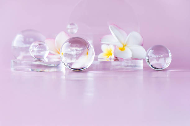 Delicate arrangement of glass orbs on a soft pink surface with white flowers and a serene atmosphere